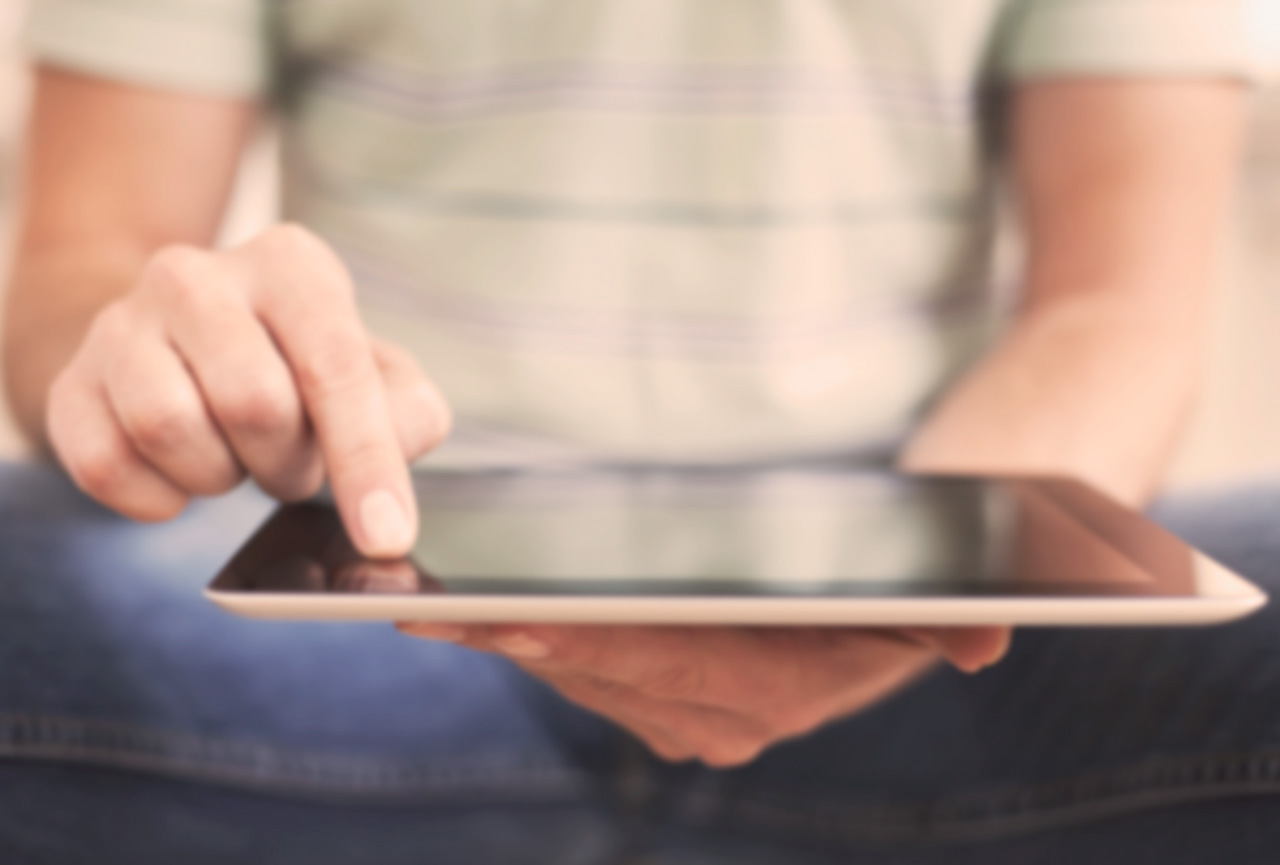 Close-up of a person's hands using a tablet device, soft neutral tones, calm focused mood.